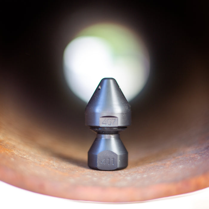 US Jetting RPD Egghead Penetrator nozzle made of case‑hardened steel, shown seated inside a pipe with engraved markings visible, featuring a rounded nose and two‑piece removable cap for easy cleaning; high‑pressure sewer jetting nozzle engineered with forward and rear jets for penetrating blockages, heavy grease, and root masses, compatible with 1/2", 3/4", and 1" hoses and rated for 14–65 GPM at 2,000–10,000 PSI.