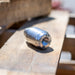 Stainless steel high‑pressure jetting nozzle on wooden pallet, precision‑machined industrial cleaning and cutting component with threaded inlet and bolted end cap, engineered for hydro‑excavation and surface preparation using rotating zero‑degree water stream performance.