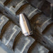 Root Ripper rotating sewer jetting nozzle resting on a heavy‑duty tire, featuring an offset orbital forward jet for blasting through roots, grease, and hard deposits in 4–8 inch pipes, with four angled rear propulsion jets designed to push debris down the line during cleanout jetting.