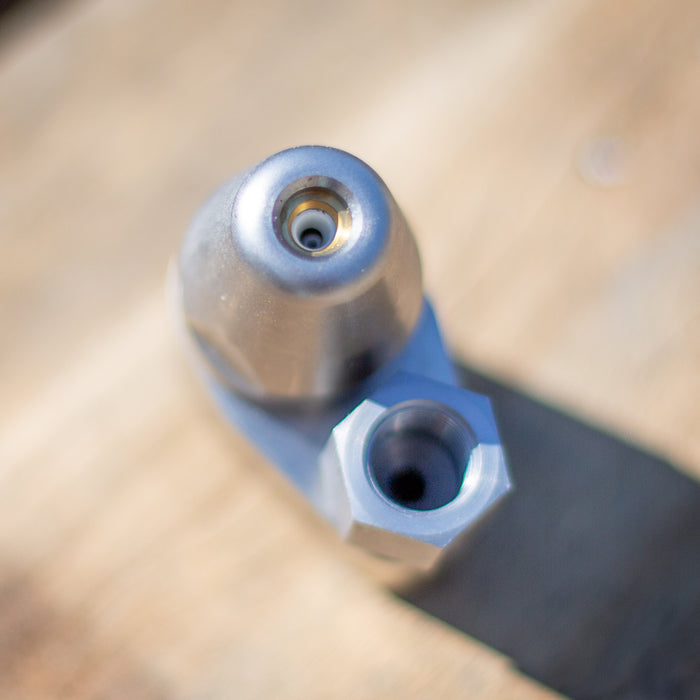 ENZ Bend Rotodrill sewer jetting nozzle with tapered front, rotating jet insert, and hex‑base connection, shown in close‑up on a workbench; 2¾‑inch bend‑negotiating design for clearing roots, debris, and blockages in 3–6 inch pipes at flows as low as 4 GPM, available in 1/4‑inch and 3/8‑inch connections.