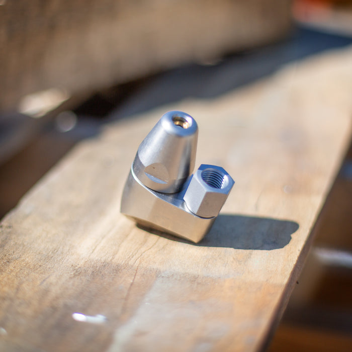 ENZ Bend Rotodrill sewer jetting nozzle with stainless‑steel tapered front and hex‑base connection, shown in close‑up on a wooden workbench; 2¾‑inch rotating jet nozzle designed to negotiate bends and traps while clearing roots, debris, and blockages in 3–6 inch pipes at flows as low as 4 GPM, available in 1/4‑inch and 3/8‑inch connections.