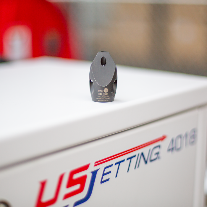 Enz Chisel Nozzle for sewer jetting shown in close‑up on a US Jetting 4018 machine, featuring a Swiss‑made stainless steel body with forward‑firing cutting jets and rear thrust jets. High‑pressure chisel‑style sewer nozzle engineered for clearing grease, light roots, and general debris with 40% forward flow for penetration and 60% rear flow for propulsion, compatible with multiple pipe sizes for professional drain and sewer cleaning.