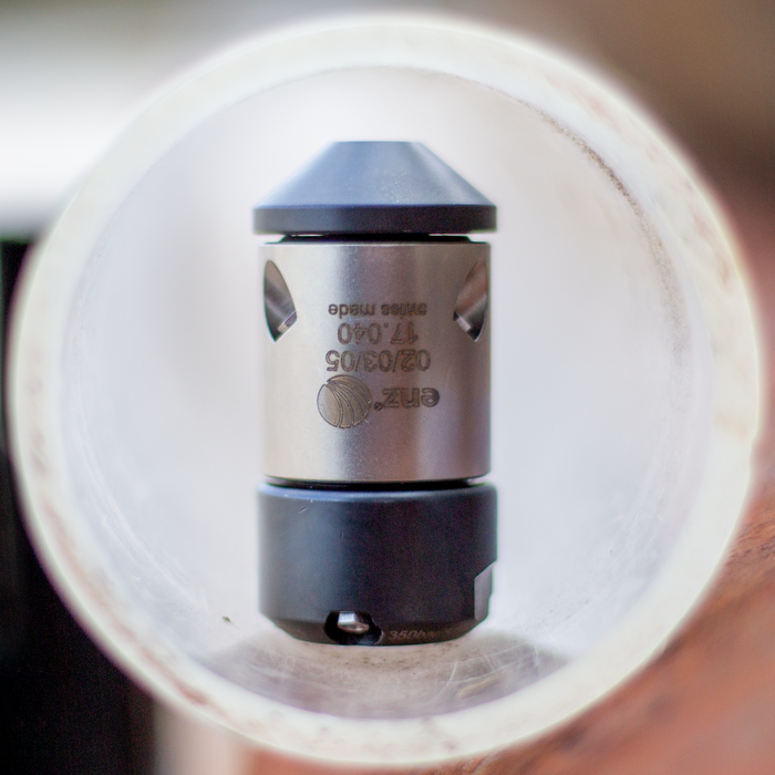 HRV Swiss‑made enz precision metal nozzle with engraved specifications, cylindrical body and conical jet head, displayed inside a clear tube; high‑performance industrial nozzle used in professional sewer, drain, and pipe cleaning applications.