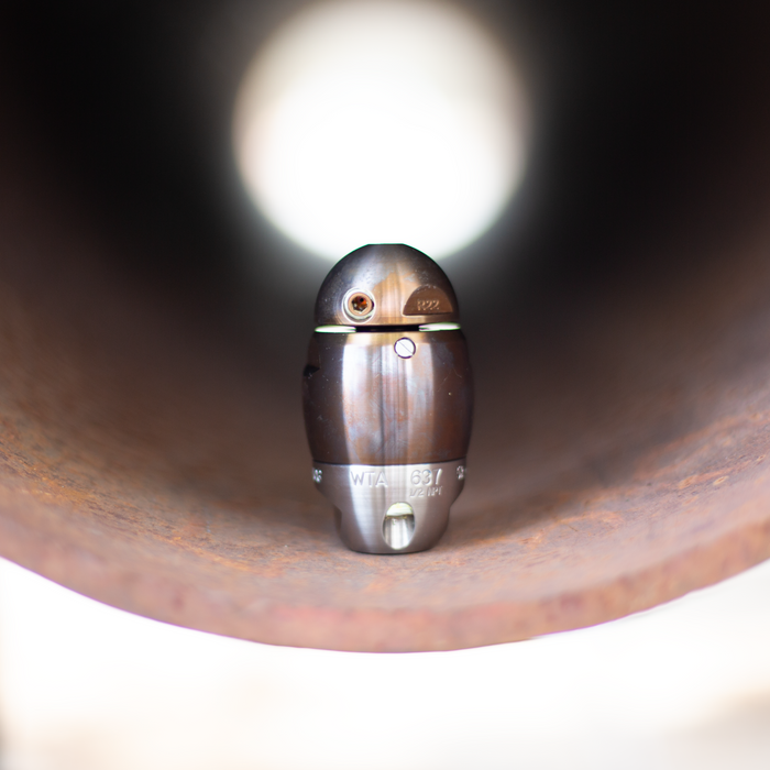 Stainless steel Warthog sewer jetter nozzle positioned inside a corroded pipe, featuring precision‑machined jet ports and a compact, high‑pressure design for pulling, descaling, and cleaning 3–8 inch sewer and drain lines. Engraved markings identify the nozzle’s model and NPT connection, highlighting its durable, rebuildable construction for professional pipeline maintenance.
