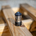 HRV Nozzle. Swiss‑made precision metal nozzle component with engraved markings, cylindrical body and conical tip, shown on a wooden workshop surface; high‑quality industrial fitting used in professional mechanical and manufacturing applications.