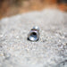USJ Penetrator 1/2-inch stainless steel sewer jetting nozzle on rough stone surface, close-up of precision-machined hex base, forward jet, and six rear jet ports engineered to break through hard blockages like packed debris or ice; high‑pressure 4018 jetter nozzle with adapters available for other hose sizes.