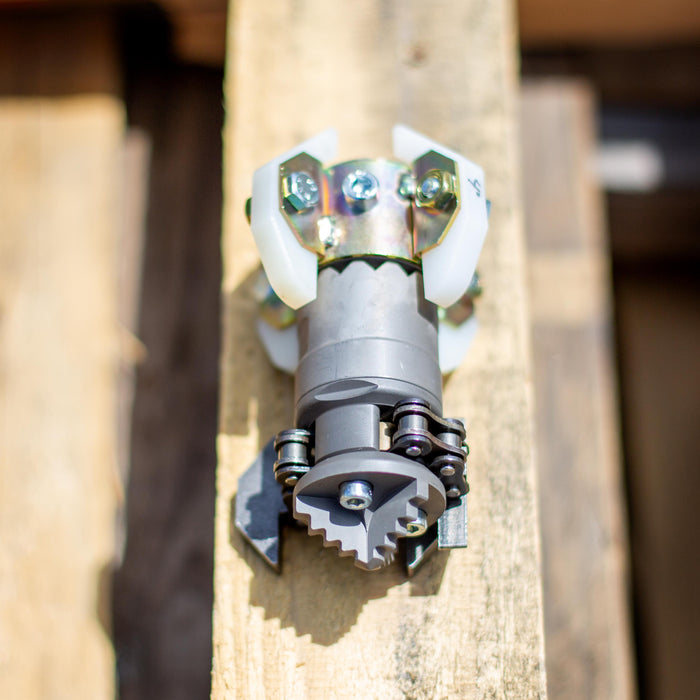 Close‑up of an ENZ Turbo Chain Scraper nozzle on a wooden pallet, showing its heavy‑duty rotating chain arms, toothed cutting head, adjustable chain lengths, and white centralizing skids. Industrial sewer jetting tool engineered for clearing concrete, roots, and grease from 3–8 inch pipes, built for rugged conditions and compatible with jetting machines requiring at least 8 GPM.