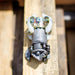 Close‑up of an ENZ Turbo Chain Scraper nozzle on a wooden pallet, showing its heavy‑duty rotating chain arms, toothed cutting head, adjustable chain lengths, and white centralizing skids. Industrial sewer jetting tool engineered for clearing concrete, roots, and grease from 3–8 inch pipes, built for rugged conditions and compatible with jetting machines requiring at least 8 GPM.
